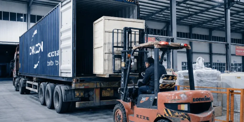 Forklift loading packed machine parts into a shipping container